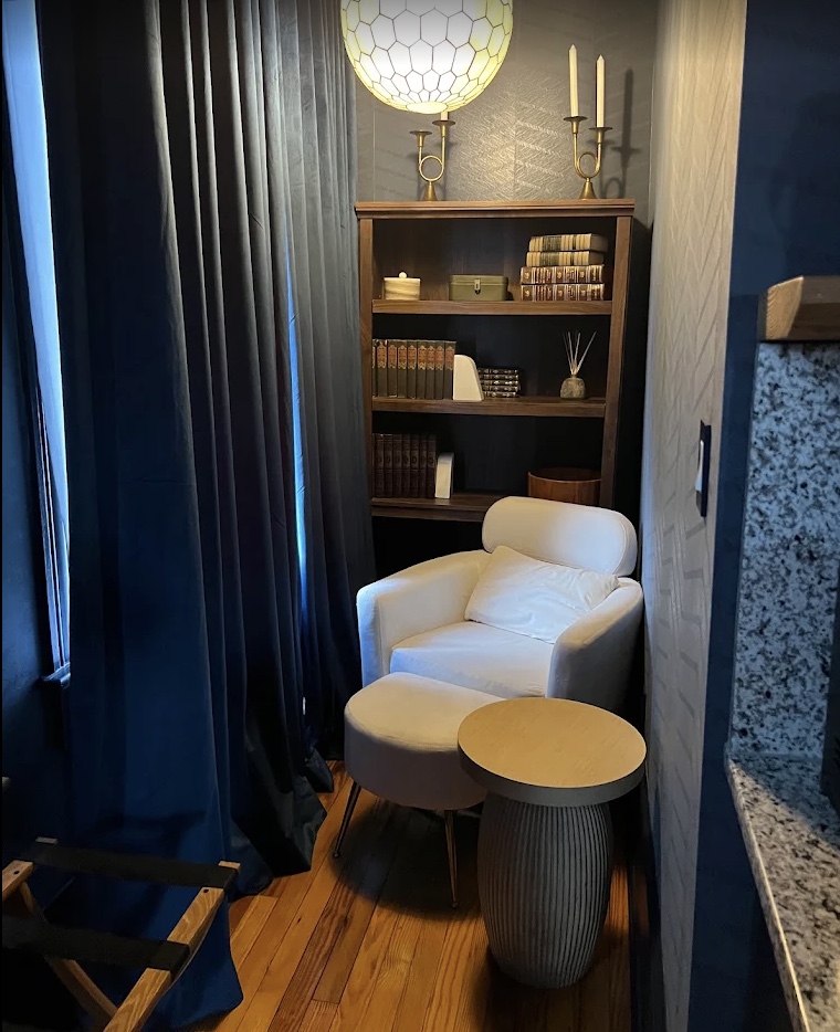 A reading nook inside The West Main — deep blue walls, a custom bookshelf and a warm pendant lamp